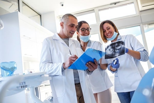 A group of cosmetic dentist offering the best in dental care examine x-rays of a CeraSmile patients teeth.